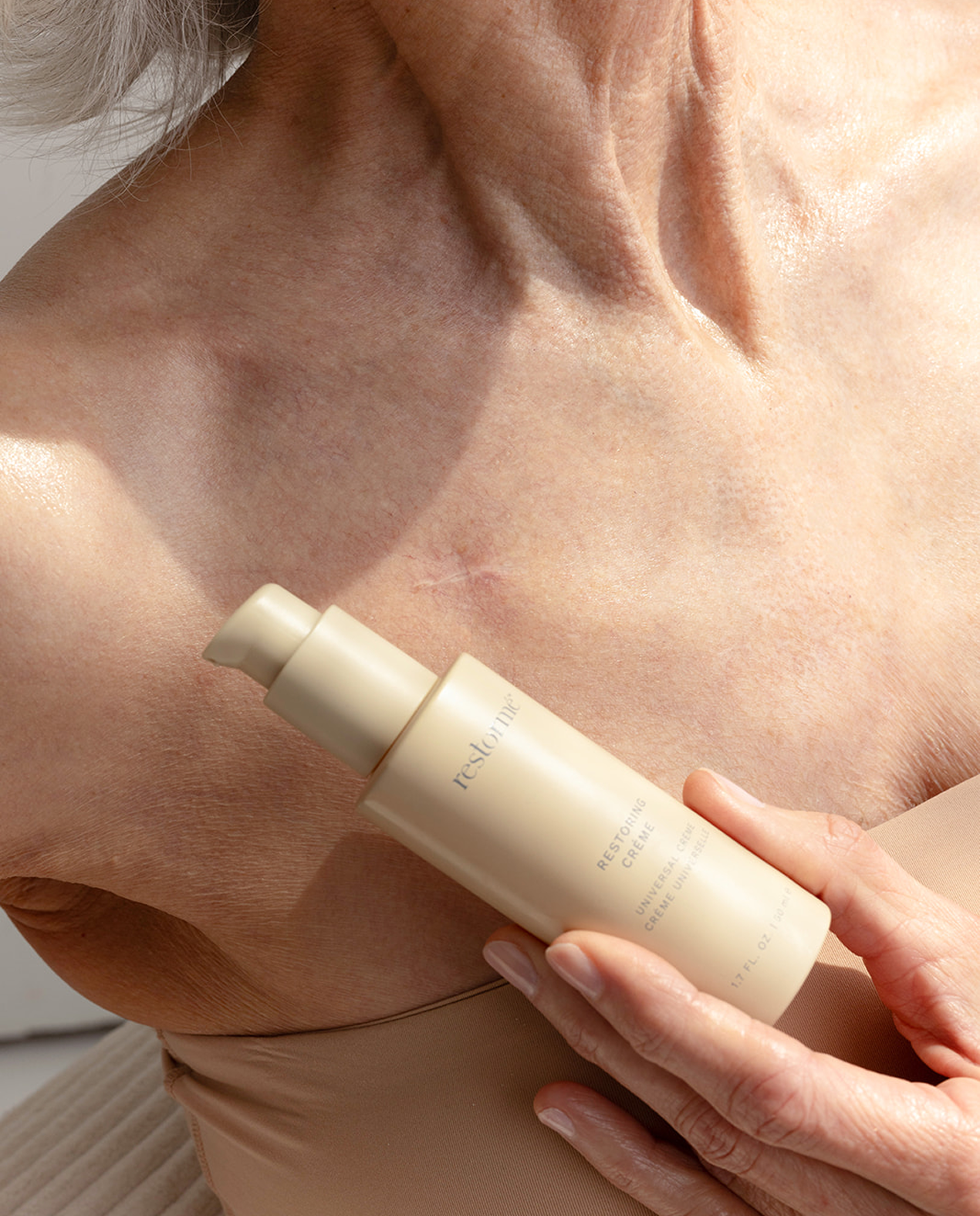 A close-up of a person's bare chest and shoulder holding a beige pump bottle against their skin, with the brand name 'pehlu' visible on the bottle.